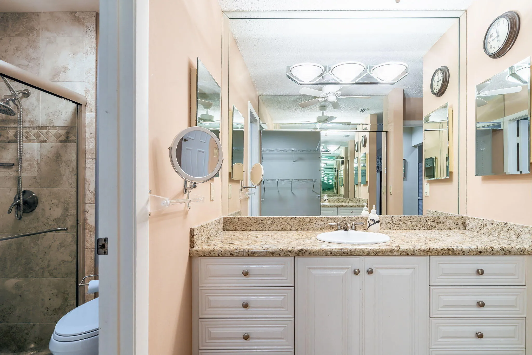 Bathroom featuring a white vanity with extensive drawer storage, a built-in sink, and a speckled countertop