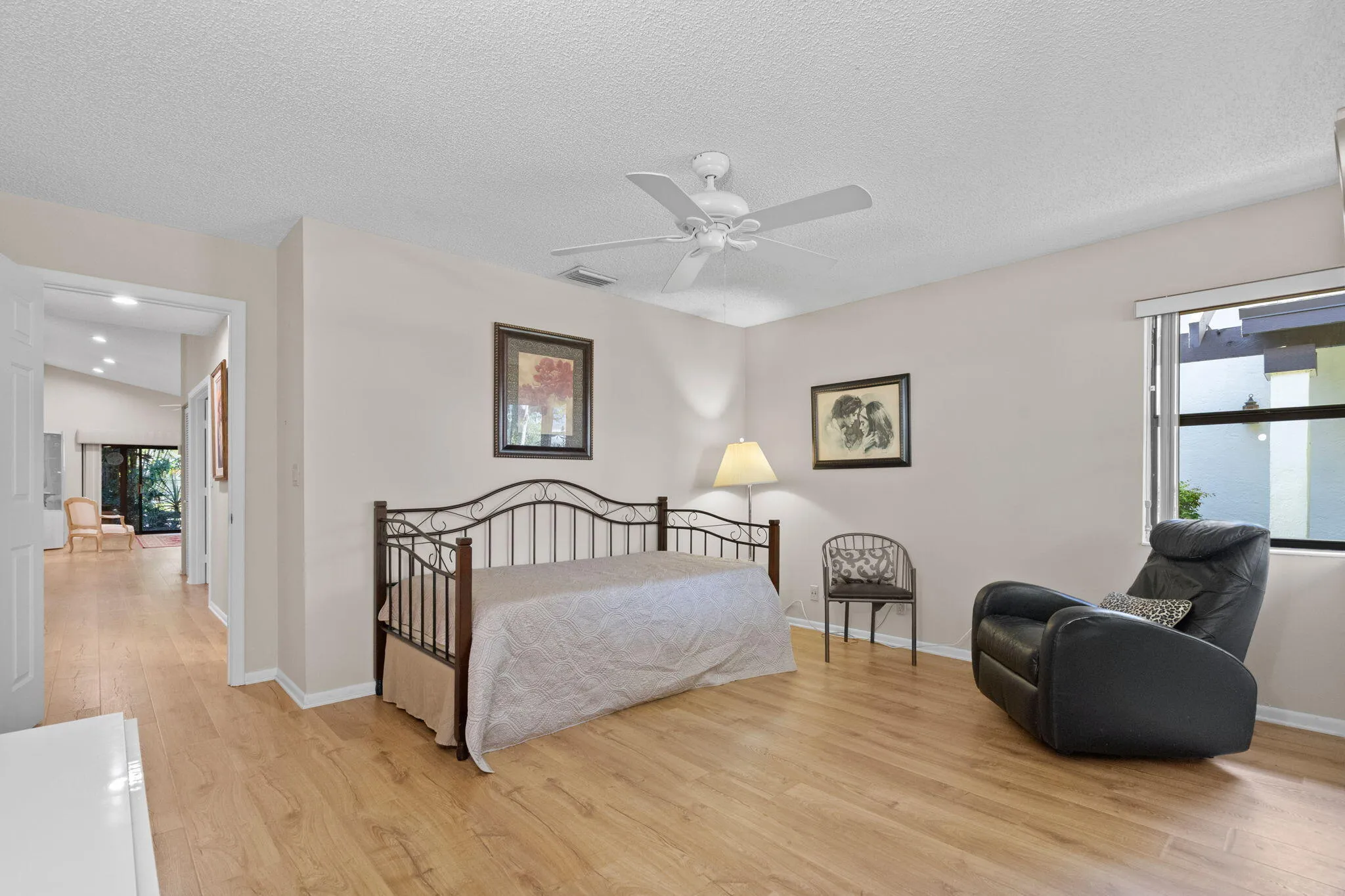 Light wood-finish flooring, white ceiling fan, and window with horizontal blinds