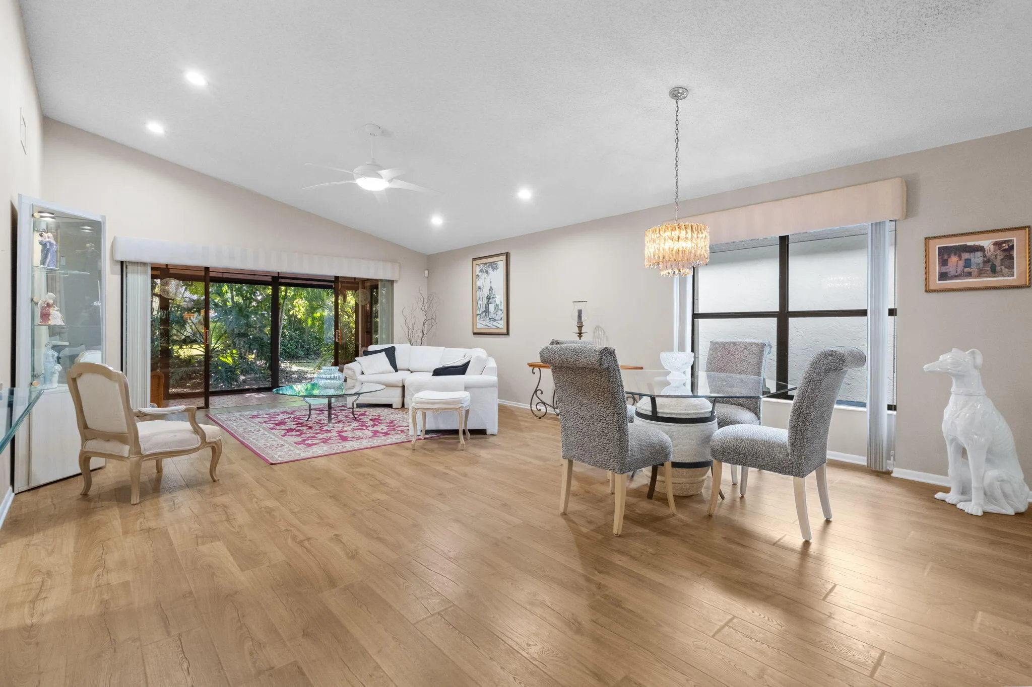 Open-concept living area with wood-finish flooring, vaulted ceilings, and recessed lighting