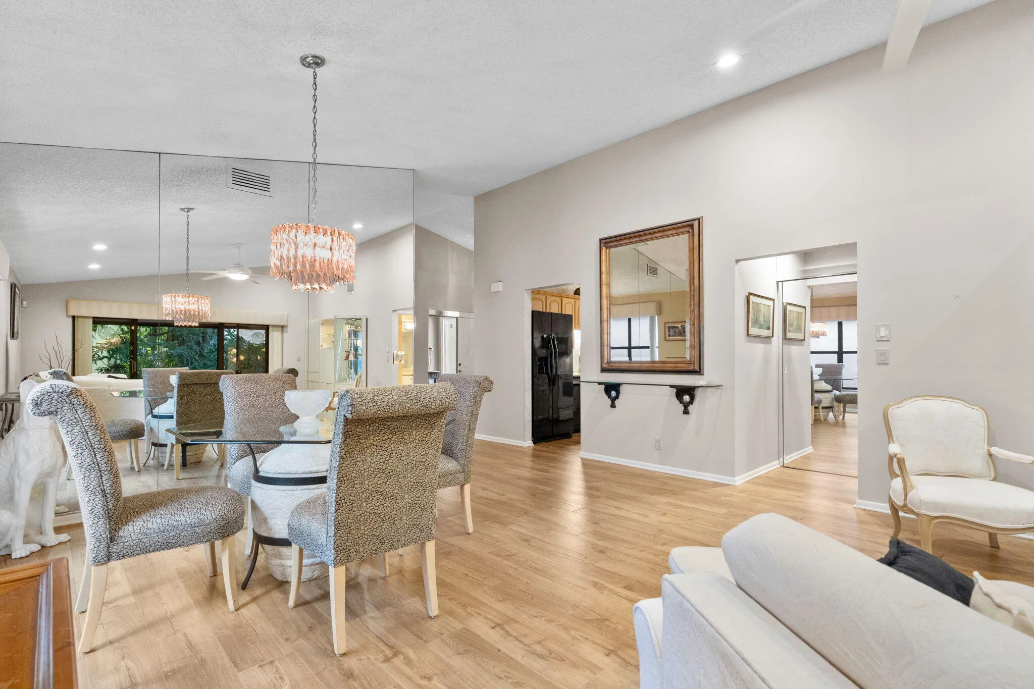 Vaulted ceilings, wood-finish flooring, recessed lighting, and a contemporary chandelier