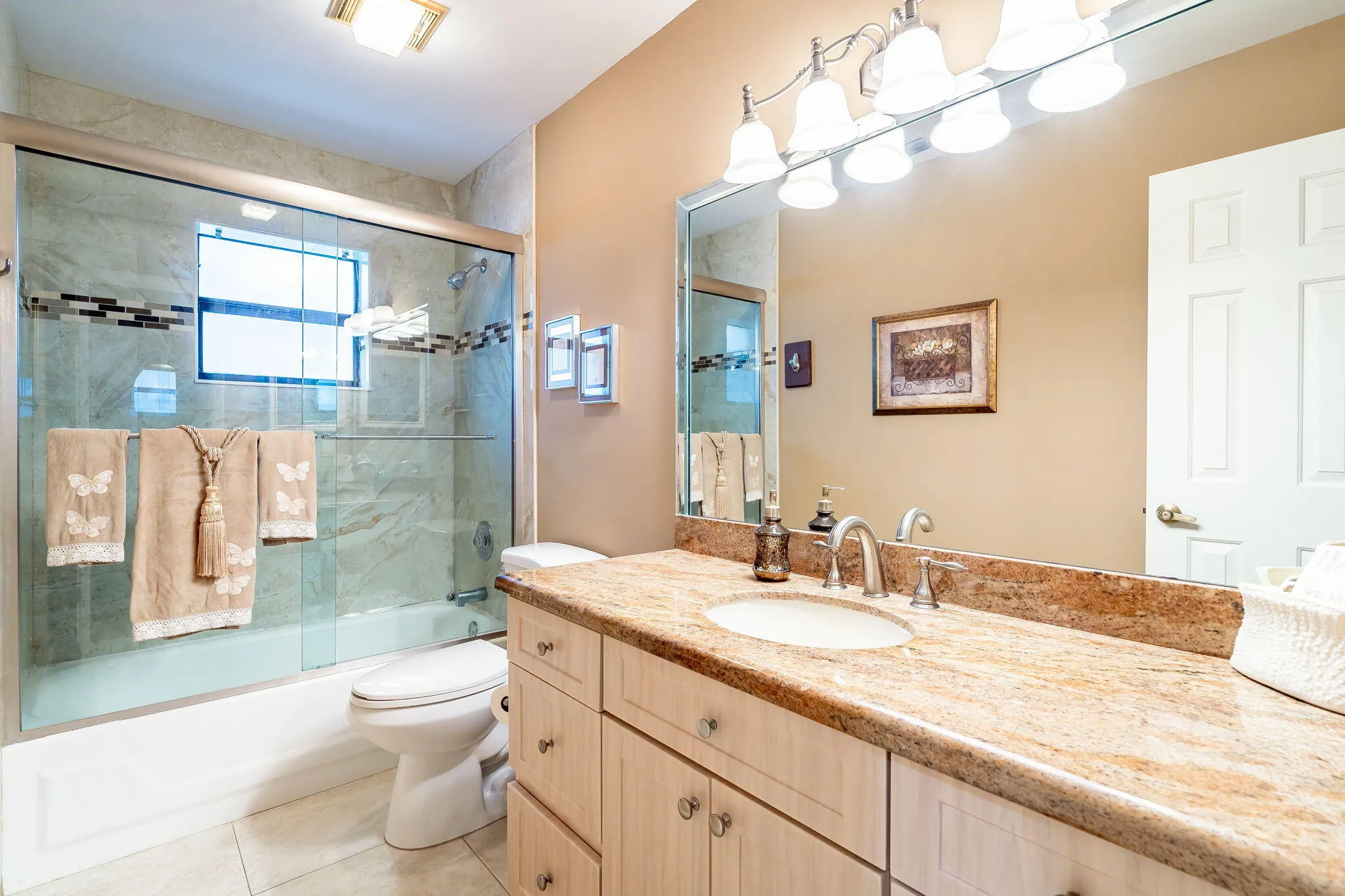 Vanity with integrated sink, stone countertop, and light wood-finish cabinetry