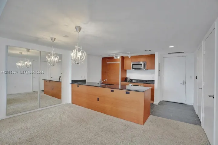 Full-length mirrored doors, two decorative chandeliers, and a kitchen island with integrated sink