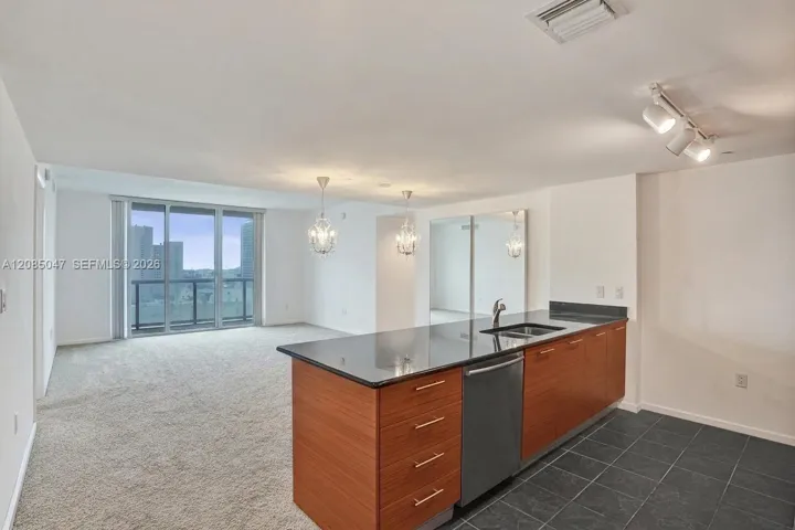 Full-height glass doors, a kitchen island with a dark countertop, wood-finish cabinetry, a stainless steel dishwasher, and tiled flooring