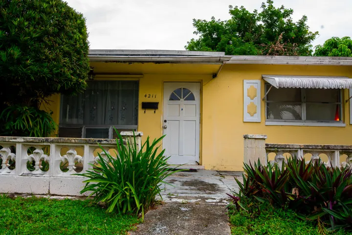 Yellow exterior with white trim, arched entry door, and ornamental window shutters