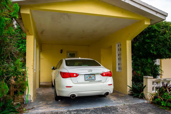 Covered parking structure with a concrete slab, yellow painted walls, and an exterior light fixture