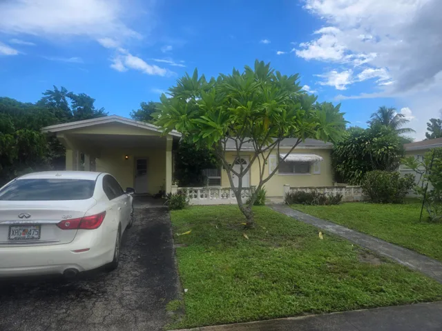 Single-story residence featuring a covered carport, paved driveway, and established landscaping