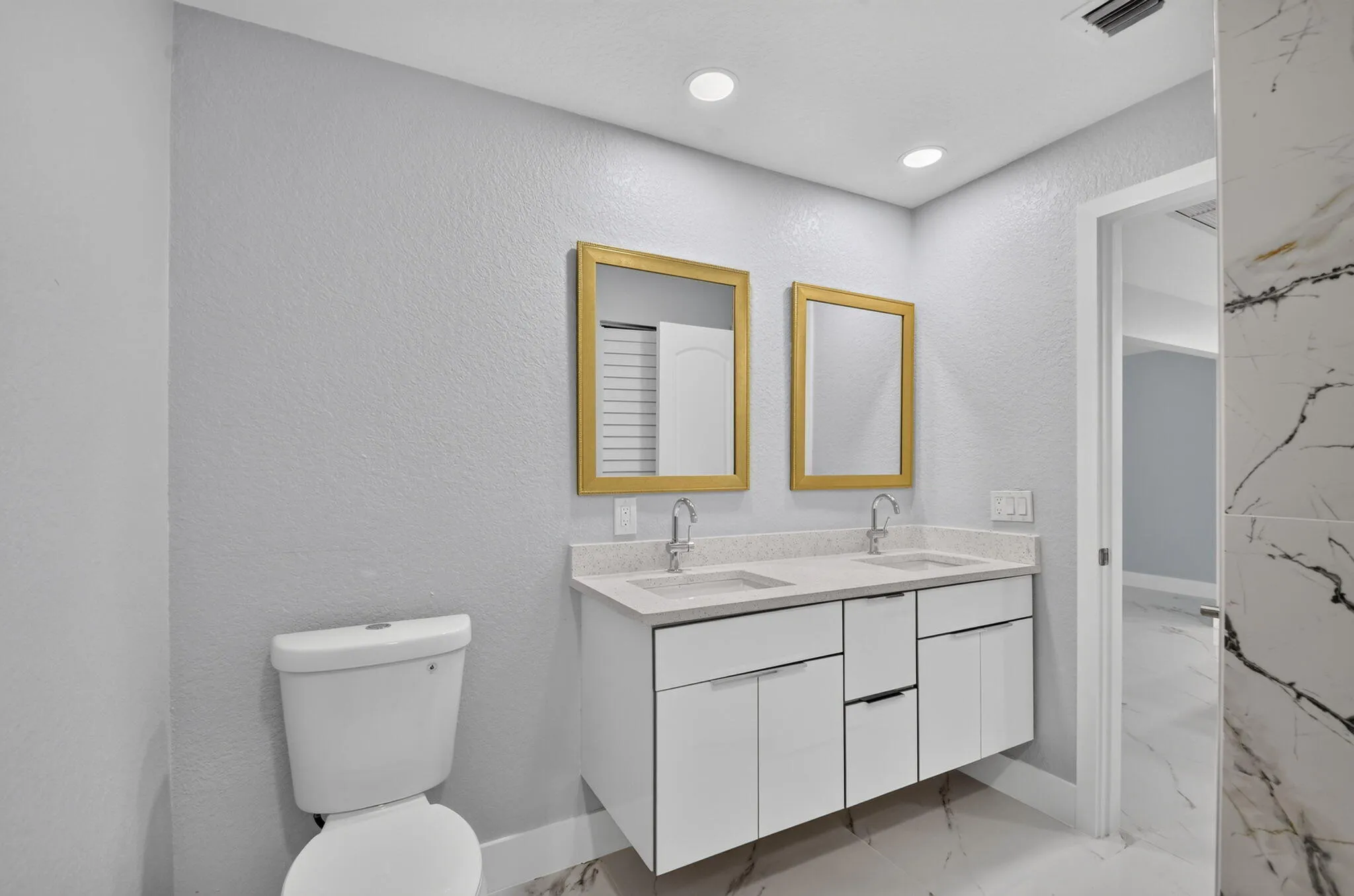 Floating dual vanity with integrated sinks and chrome fixtures, illuminated by recessed ceiling lights