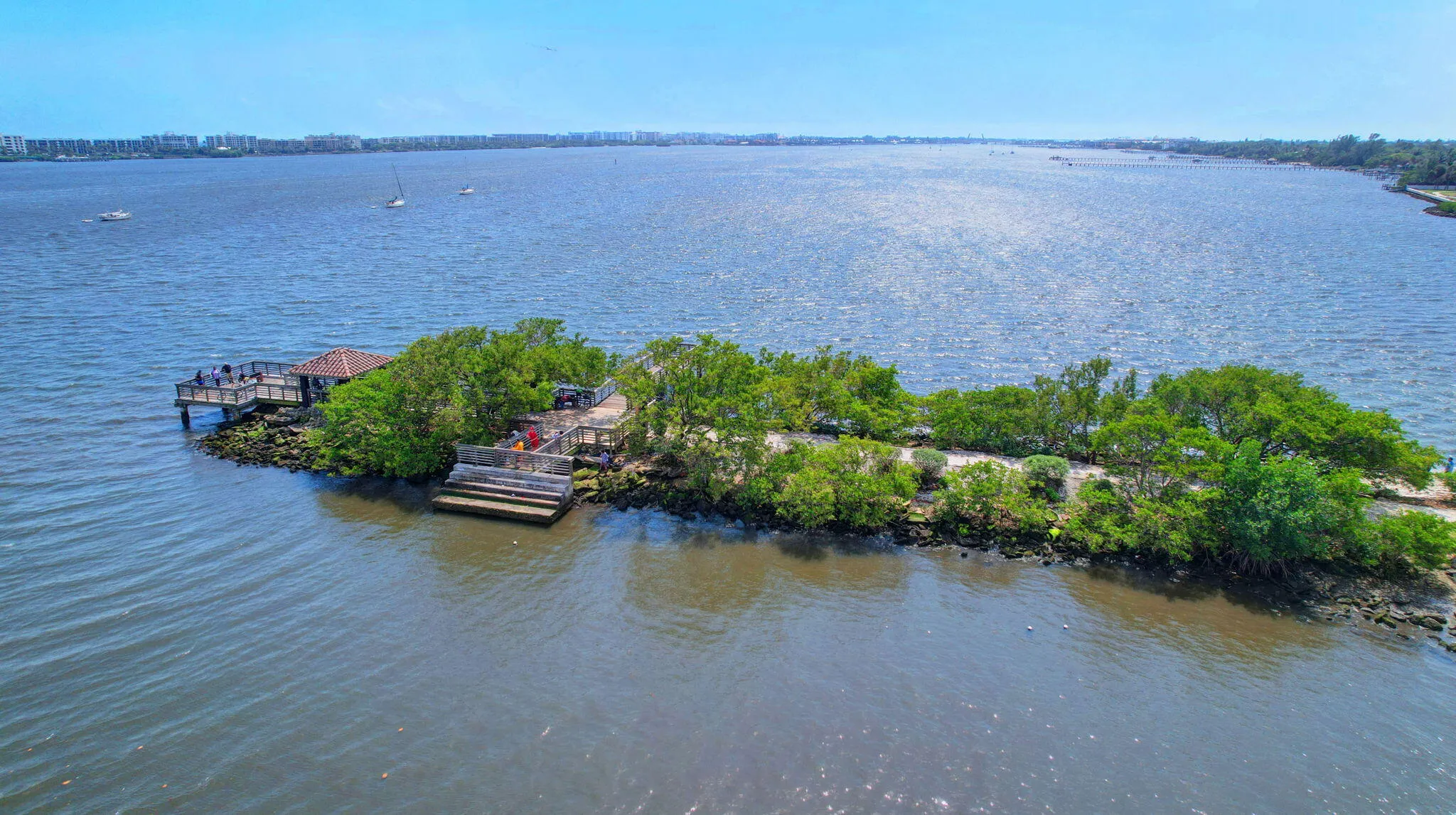 Waterfront property featuring a dock with a covered area, wood decking, and established trees
