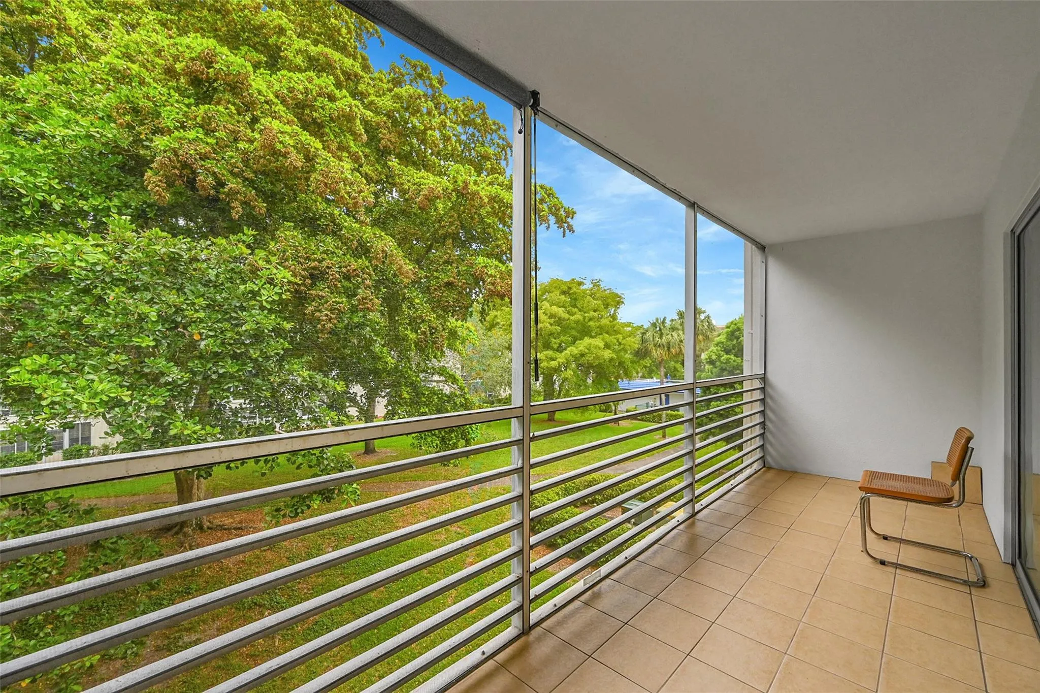 Tiled balcony with metal railings and a clear overhead structure