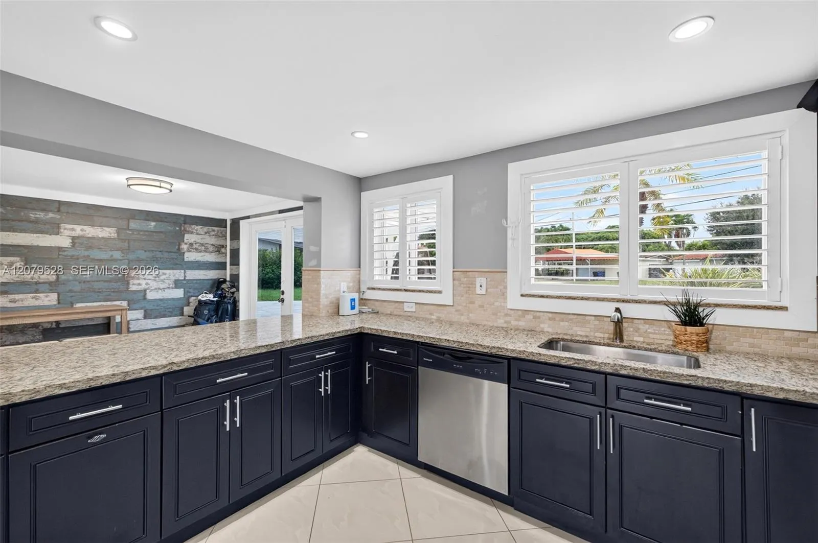 Large bright kitchen w/ windows everywhere, plantation shutters, wood cabinets, stainless appliances and granite counters