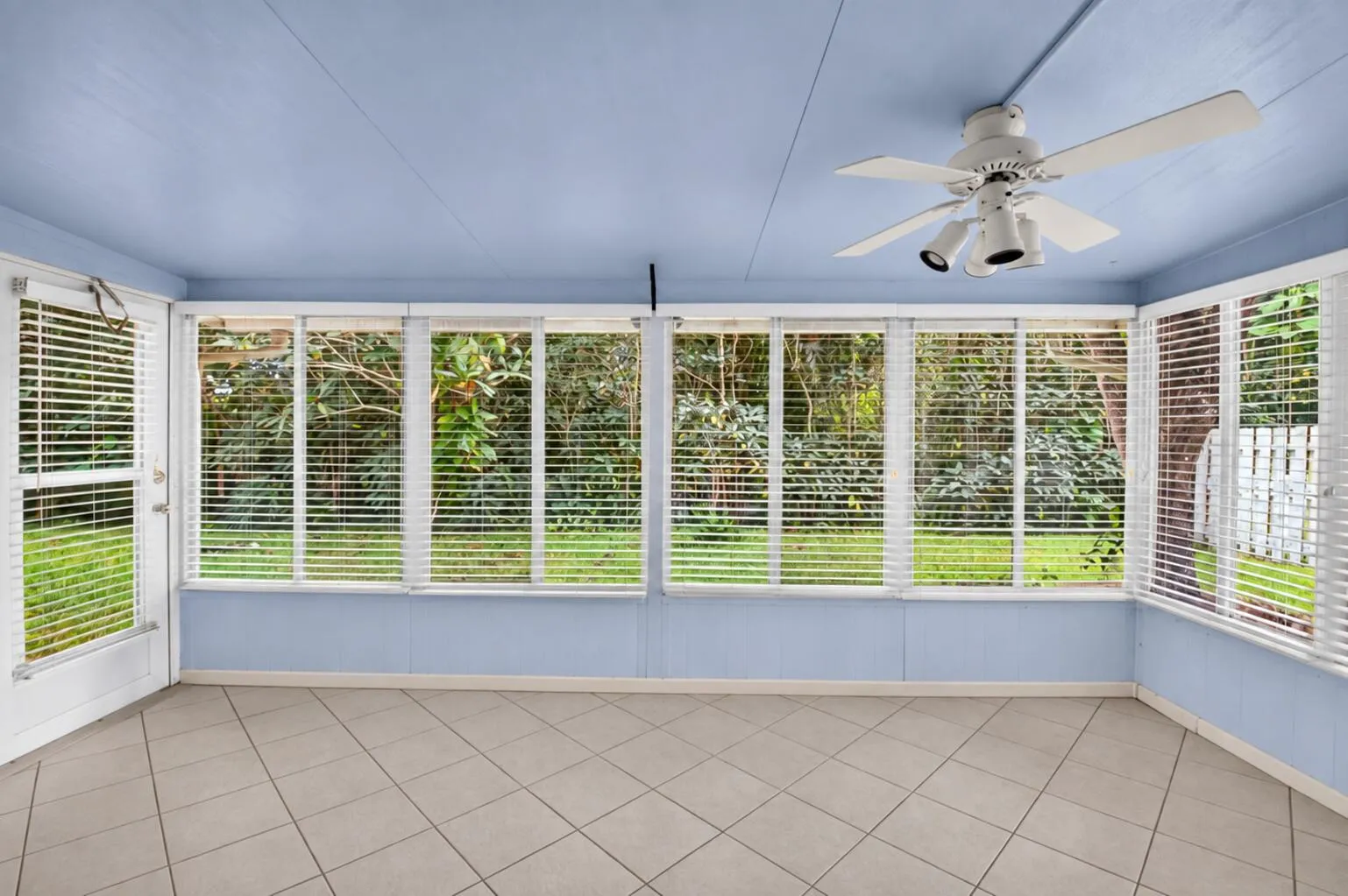 Enclosed sunroom with expansive windows and backyard views.