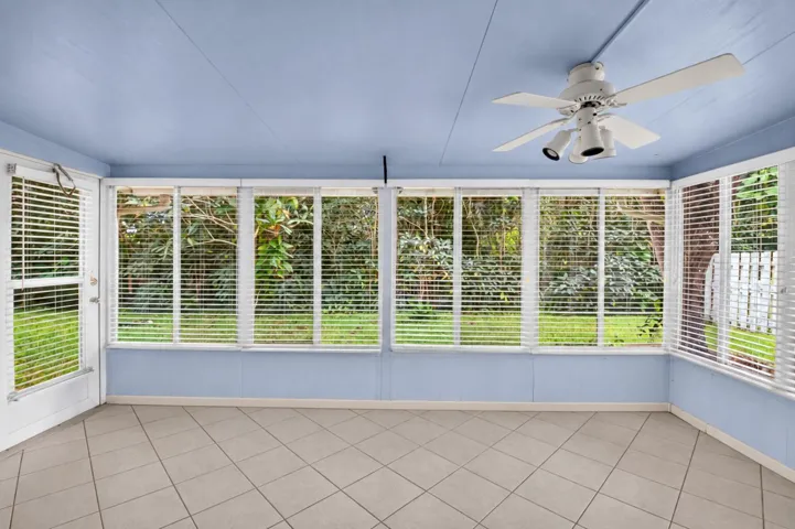 Enclosed sunroom with expansive windows and backyard views.