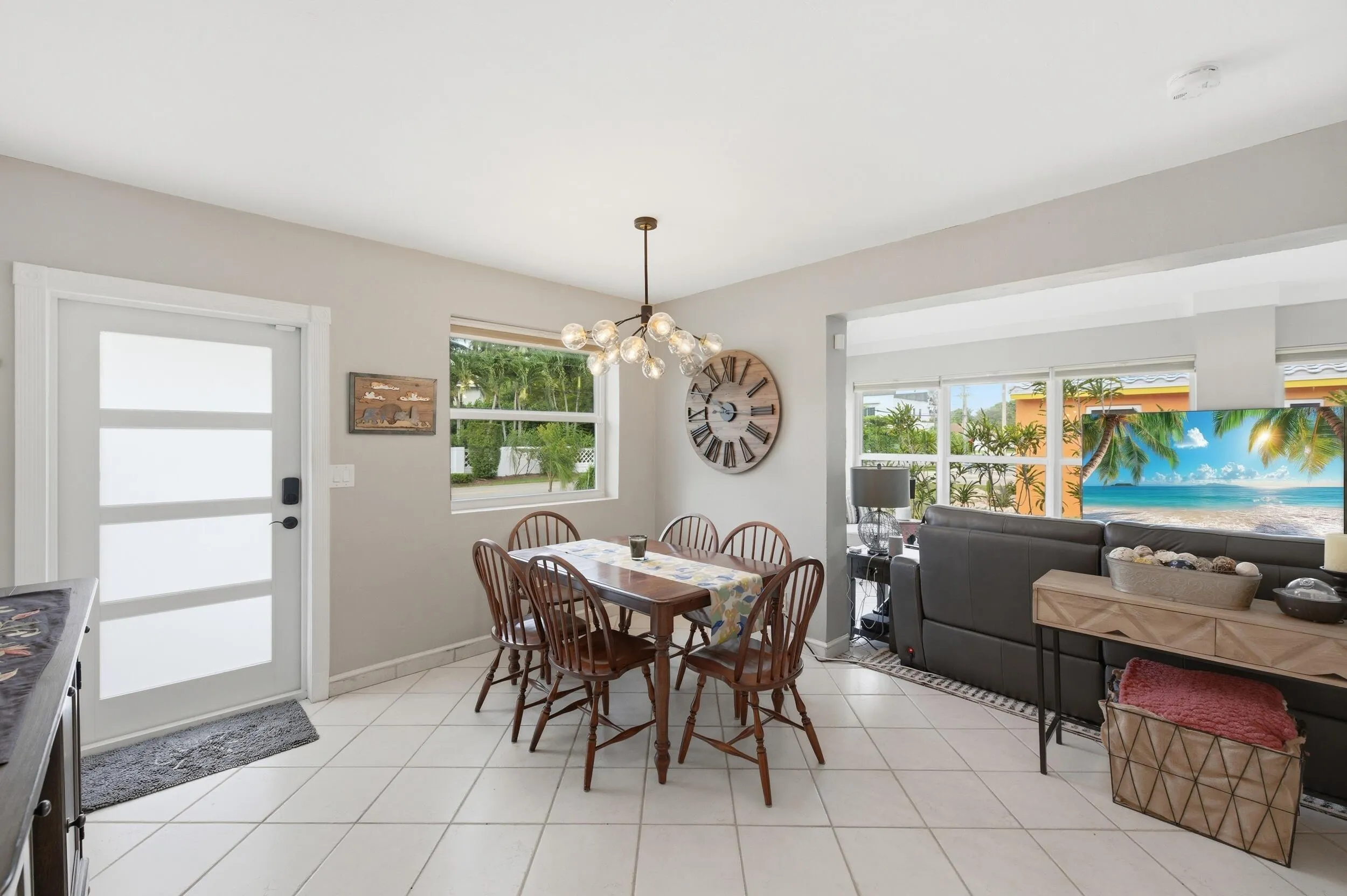 Open-concept dining area featuring tile flooring, a contemporary chandelier, and a large window