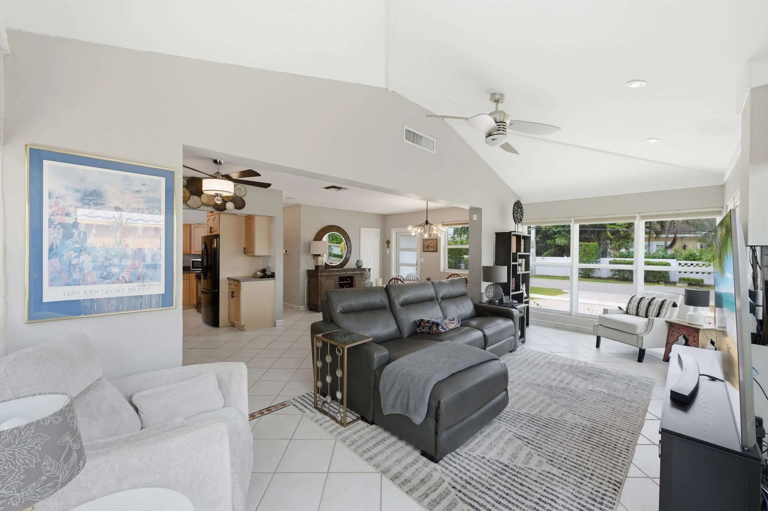 Vaulted ceilings with recessed lighting, large pane windows, tile flooring with decorative inlay, and a ceiling fan