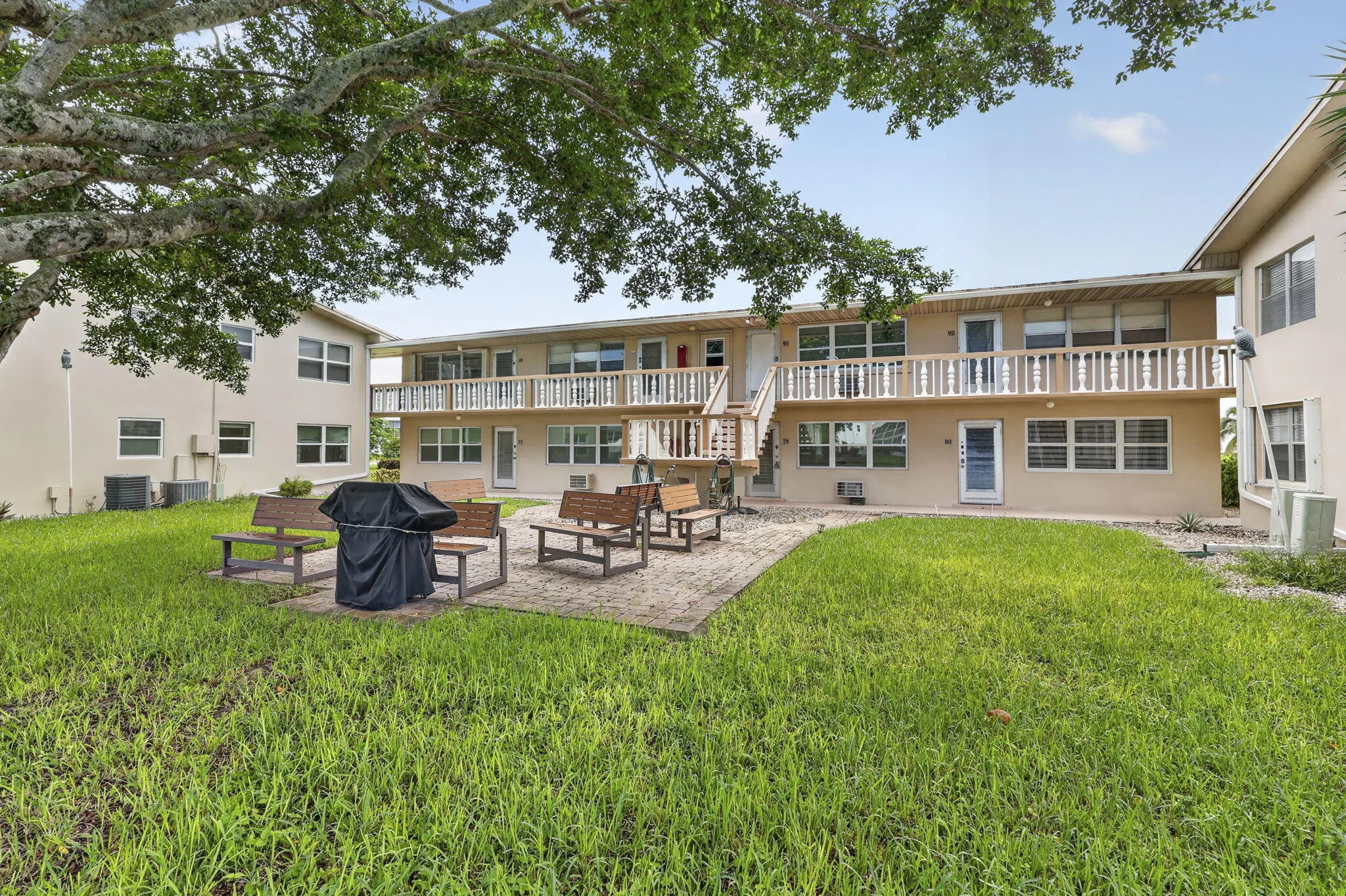 Expansive green space featuring a paved patio area with built-in wood benches