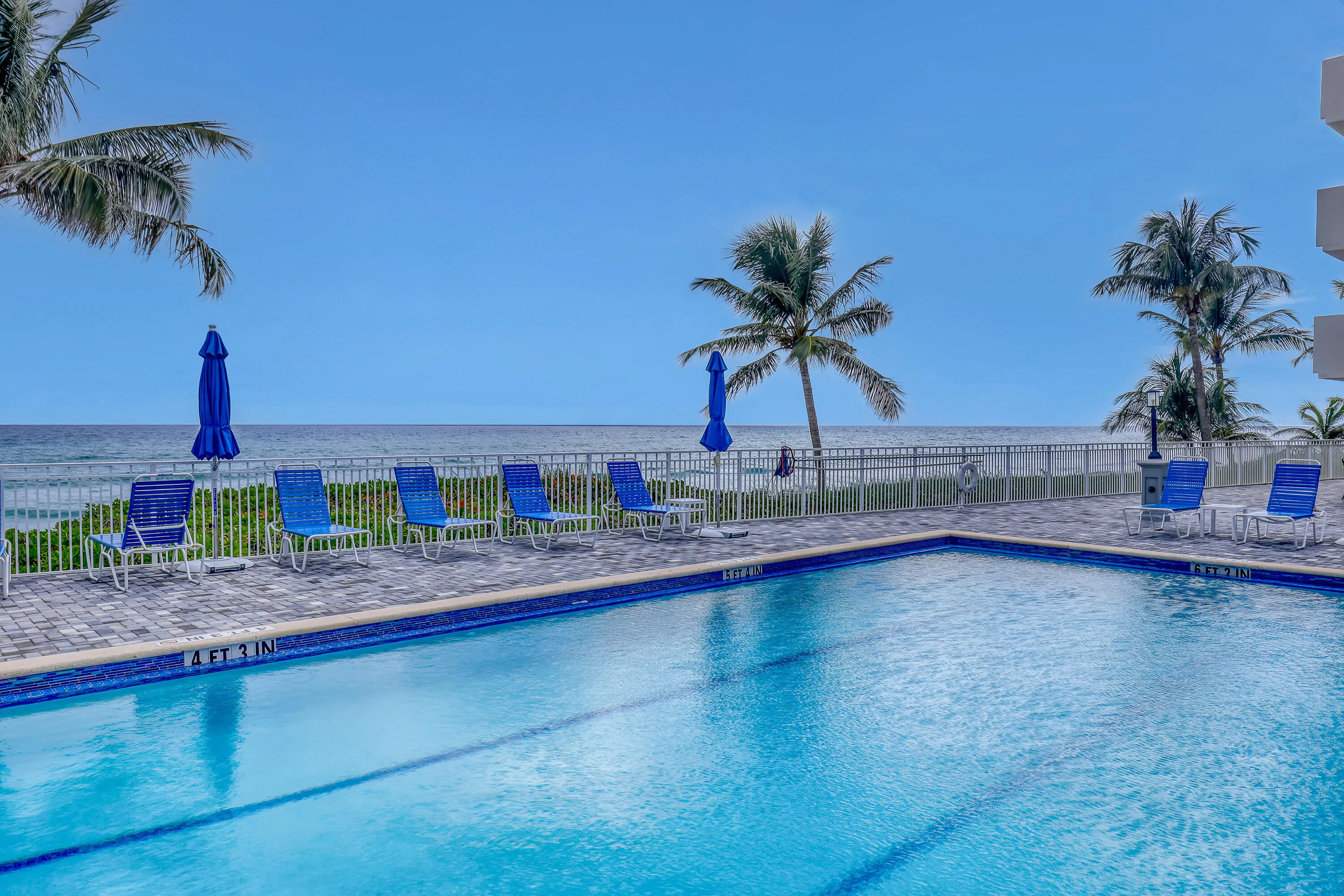 Swimming pool with blue tile surround, paver deck, and ocean backdrop