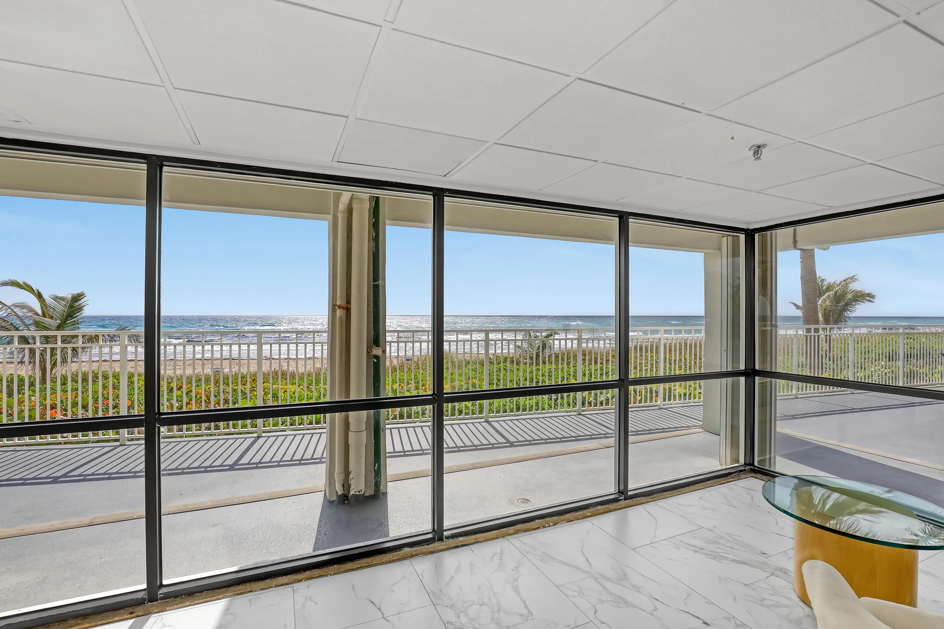 Floor-to-ceiling windows, white marble-finish flooring, drop ceiling, and balcony access with metal railings