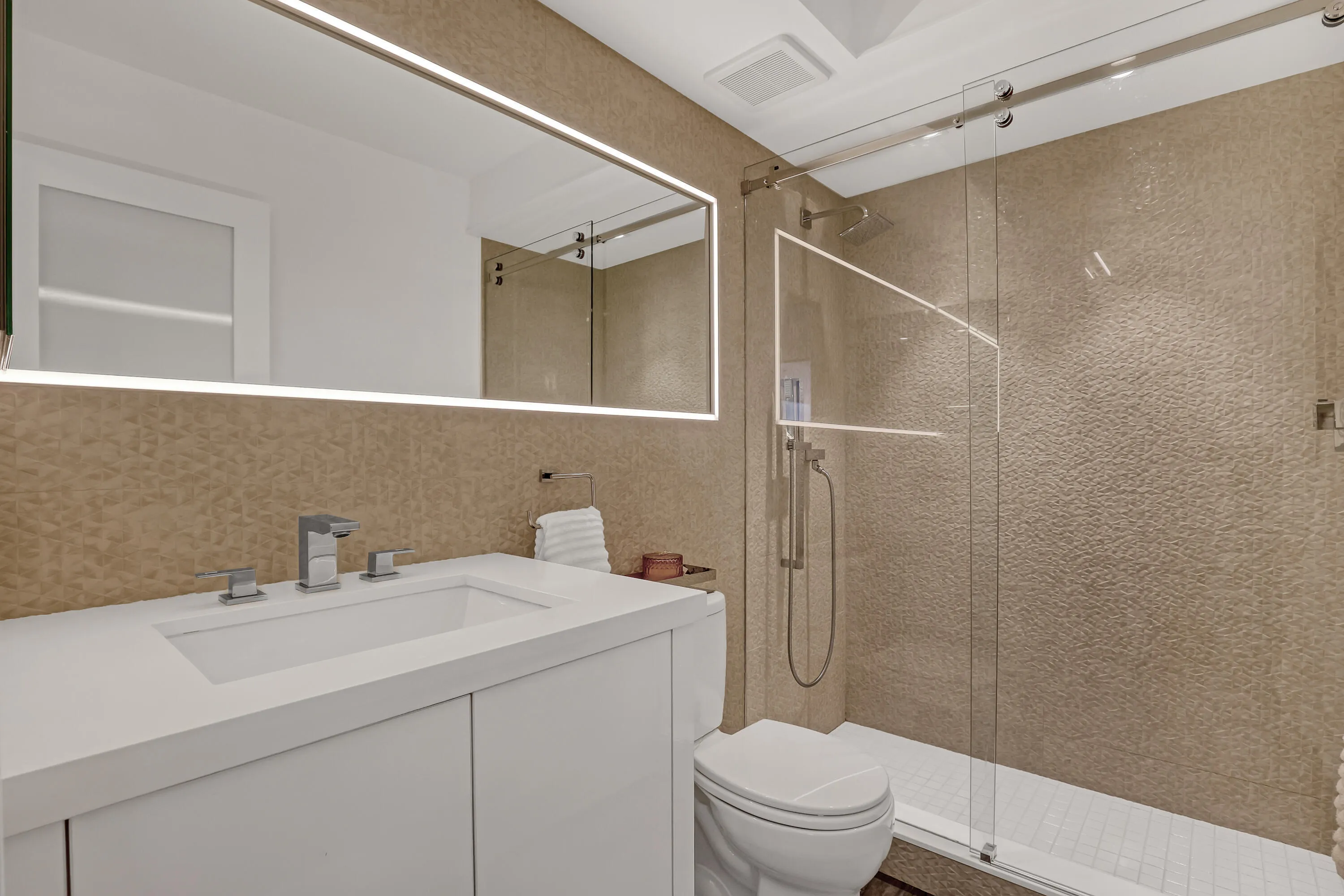 Contemporary bathroom featuring a floating vanity with integrated sink, chrome fixtures, and a frameless glass shower enclosure