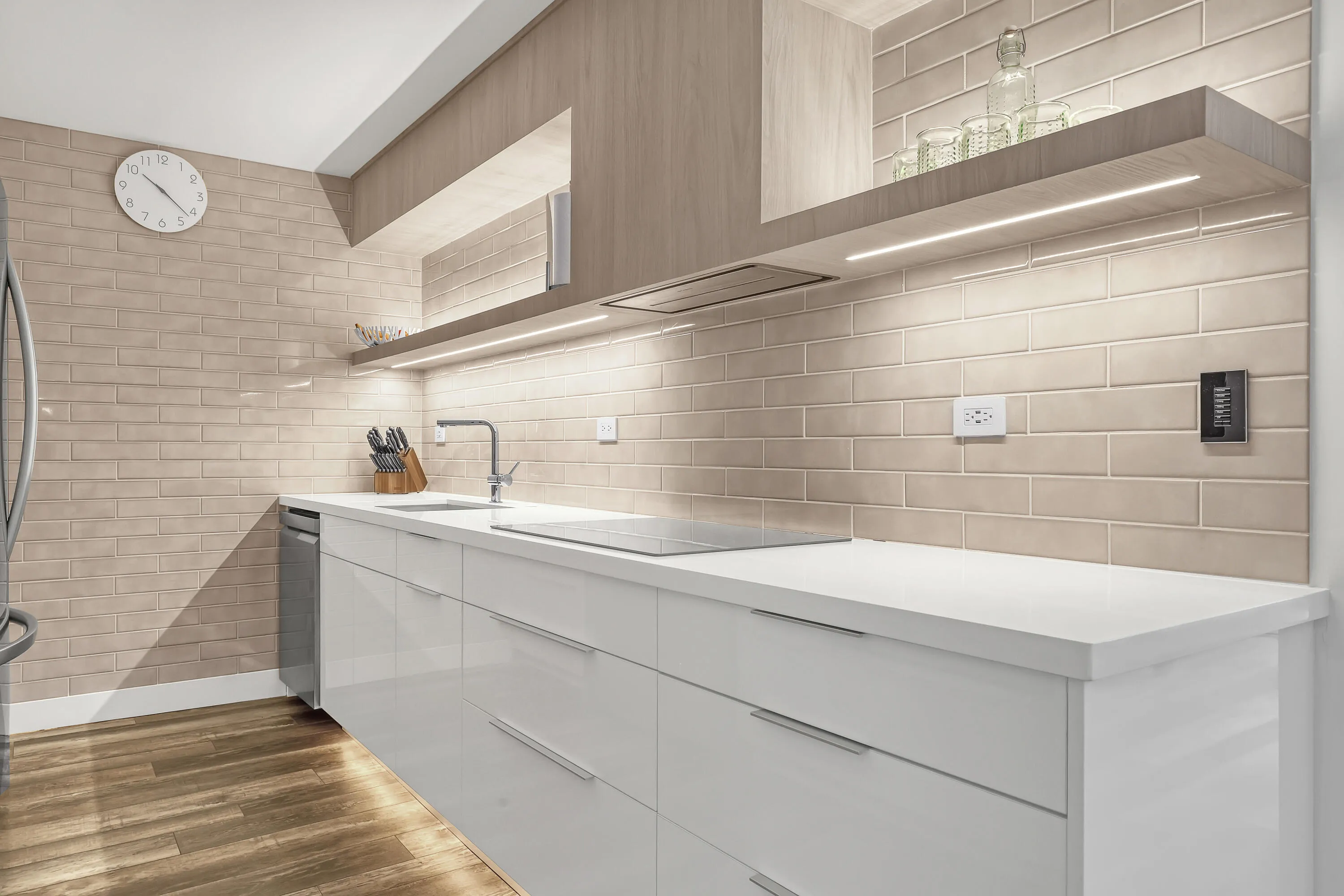 Modern kitchen featuring white cabinetry, light-toned brick-patterned tile, under-cabinet lighting, wood-finish flooring, and a built-in induction cooktop