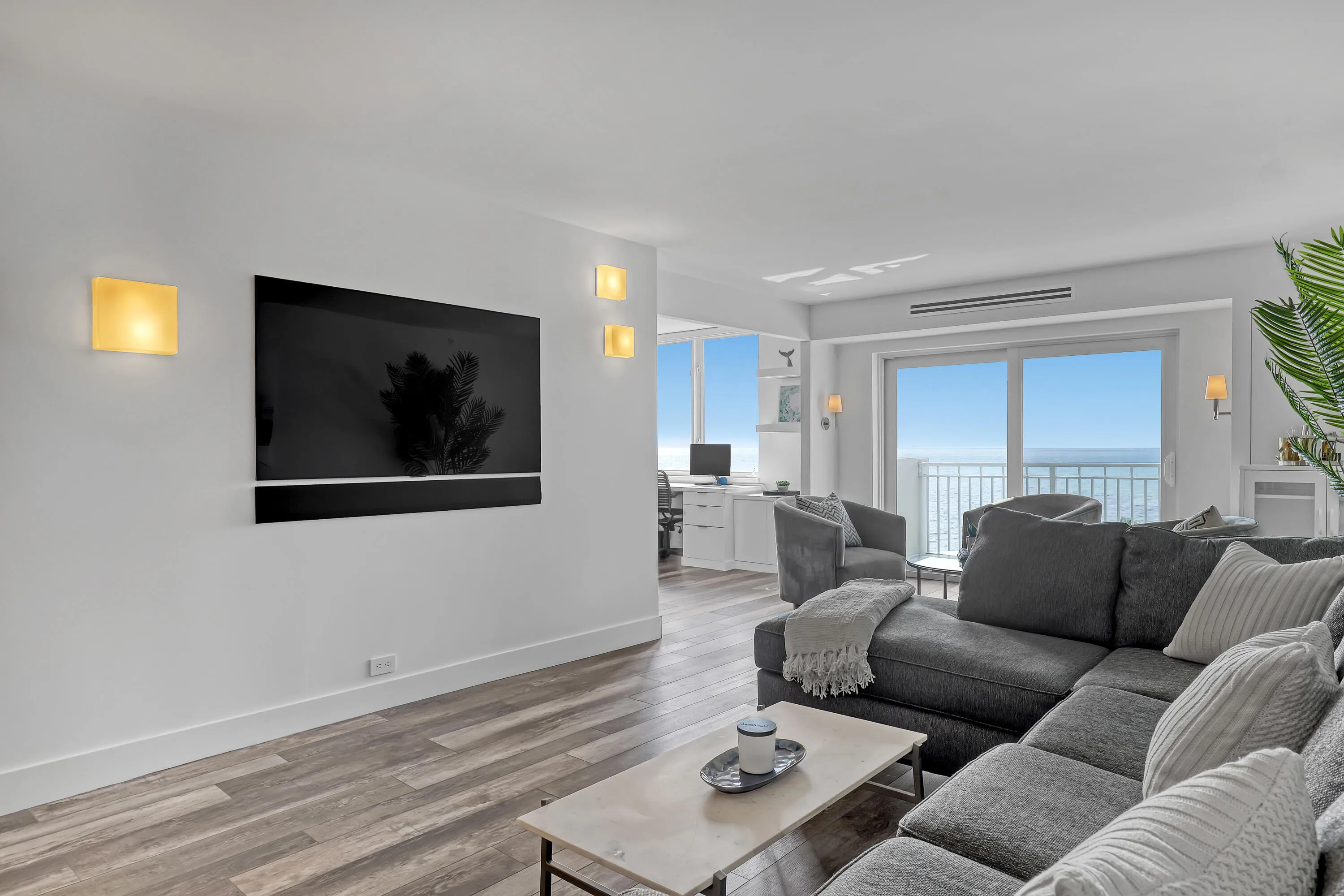 Spacious living area featuring wood-finish flooring, recessed lighting, and wall-mounted sconces