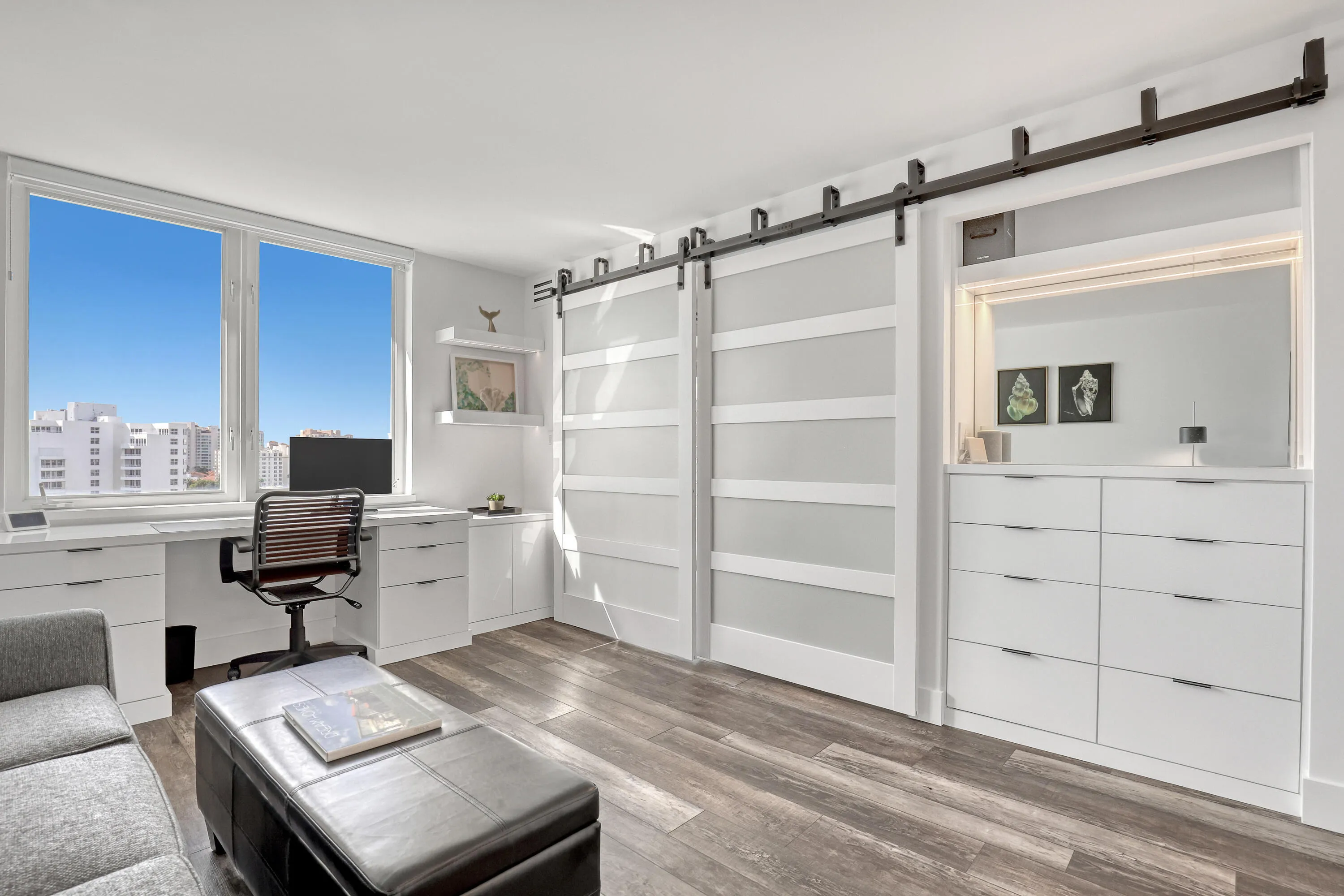 Wood-finish flooring, built-in desk cabinetry, dual sliding barn doors, built-in dresser with integrated lighting, and large windows