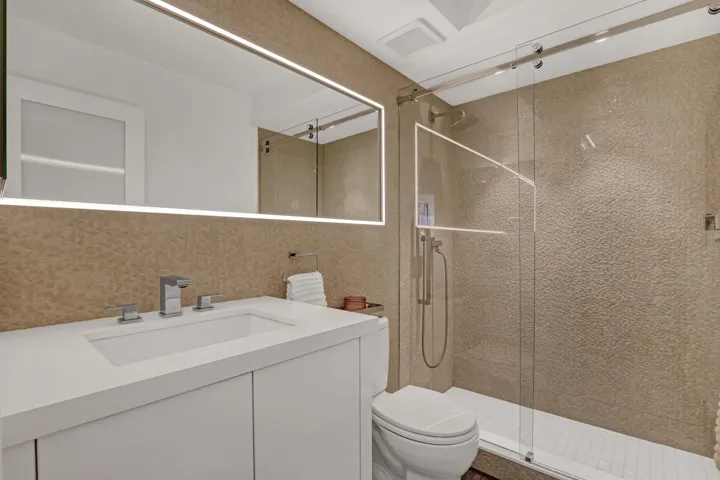 Contemporary bathroom featuring a floating vanity with integrated sink, chrome fixtures, and a frameless glass shower enclosure