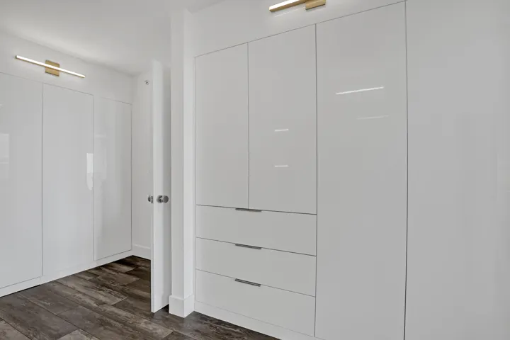 Built-in cabinetry with high-gloss white finish, integrated drawers, and wood-finish flooring