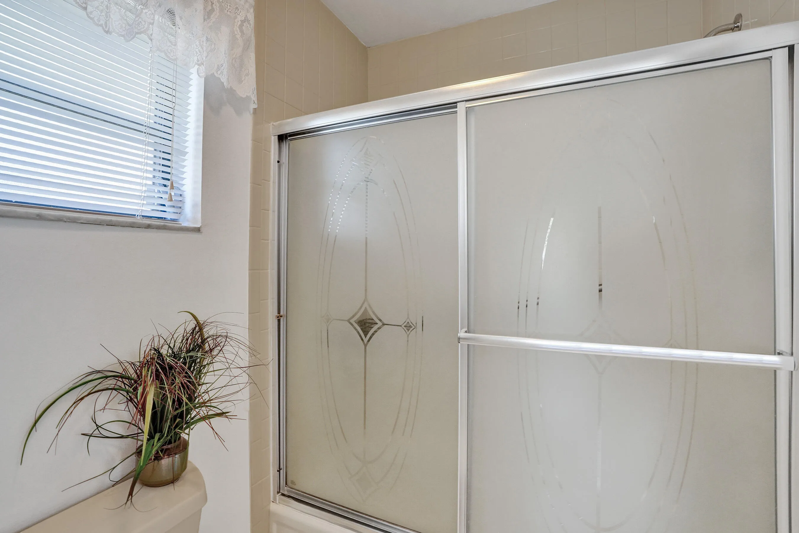 Sliding shower enclosure with frosted glass panels and aluminum framing
