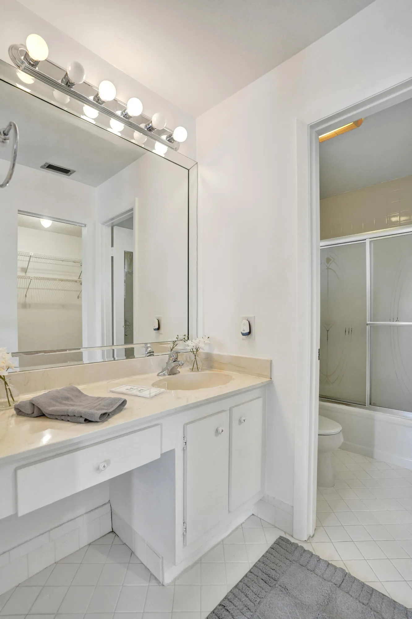 Vanity with integrated sink, ample counter space, custom cabinetry, full-width mirror, and overhead lighting