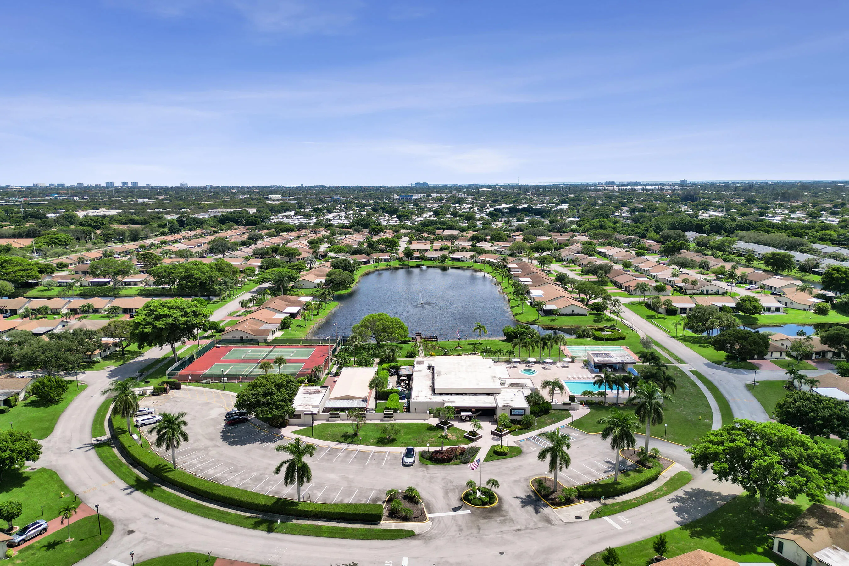 Community with central lake, tennis courts, and swimming pool