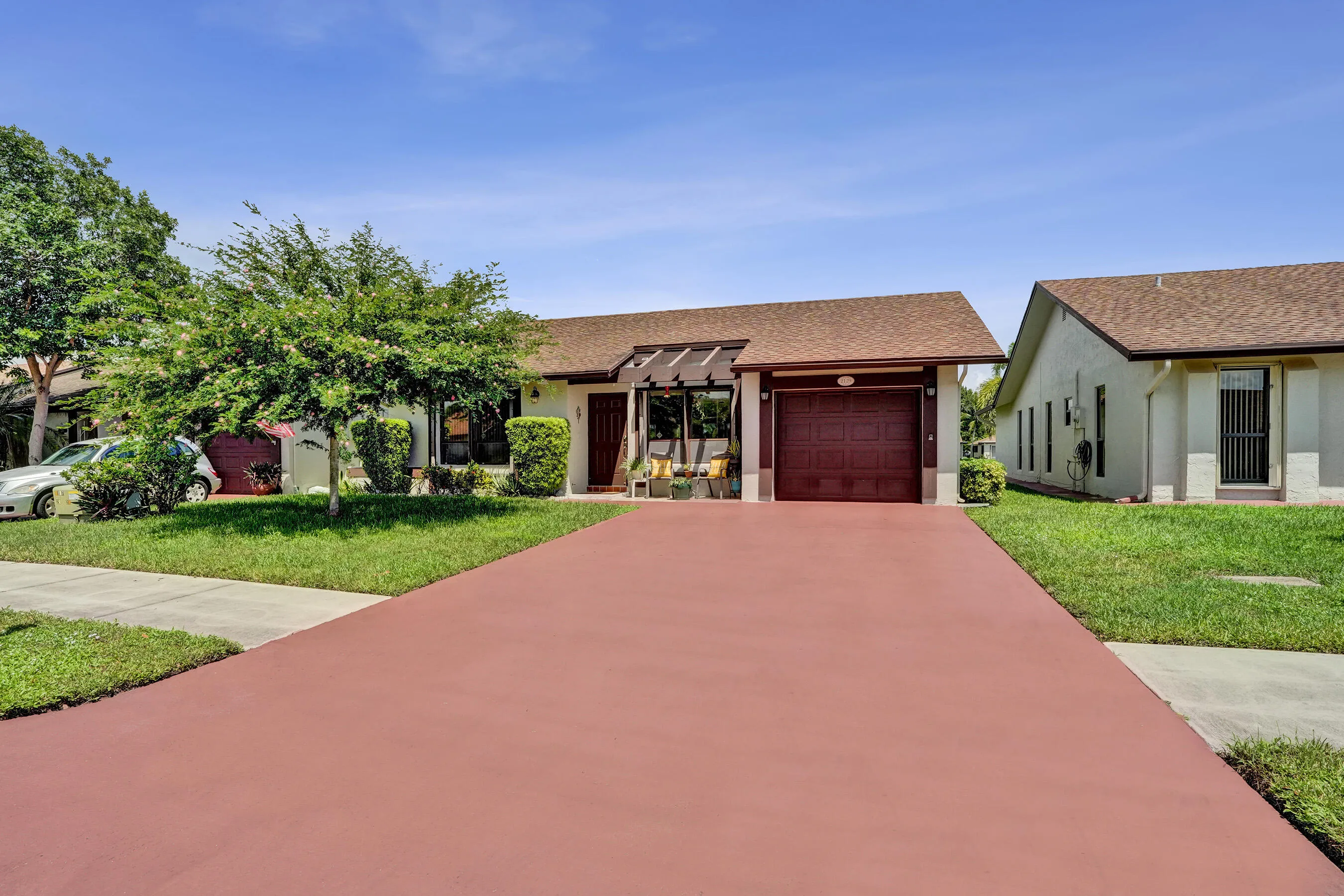 Single-story residence featuring a brown asphalt shingle roof, a red garage door, and a pergola accent