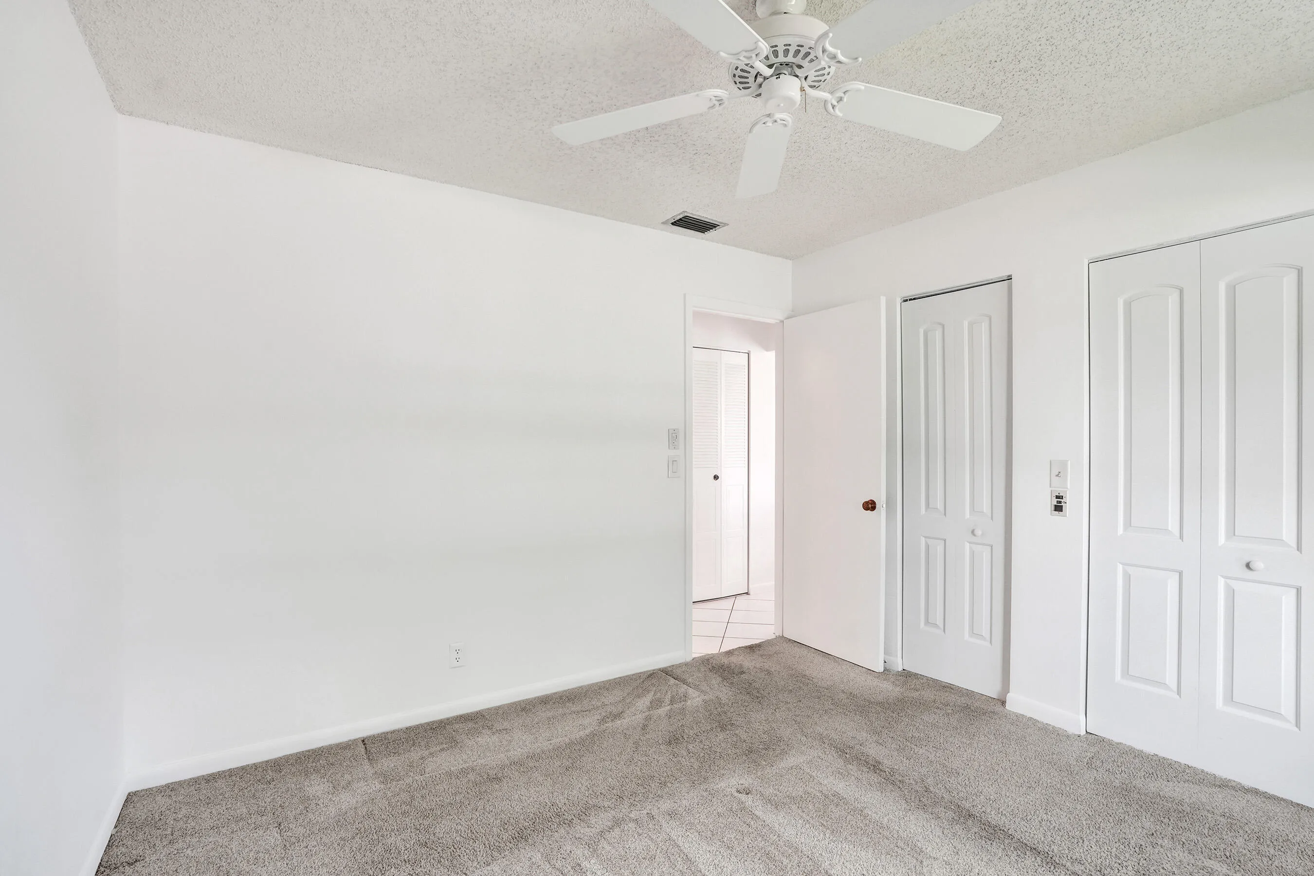 Ceiling fan with light fixture, textured ceiling, light gray carpeting, bi-fold closet doors, white walls