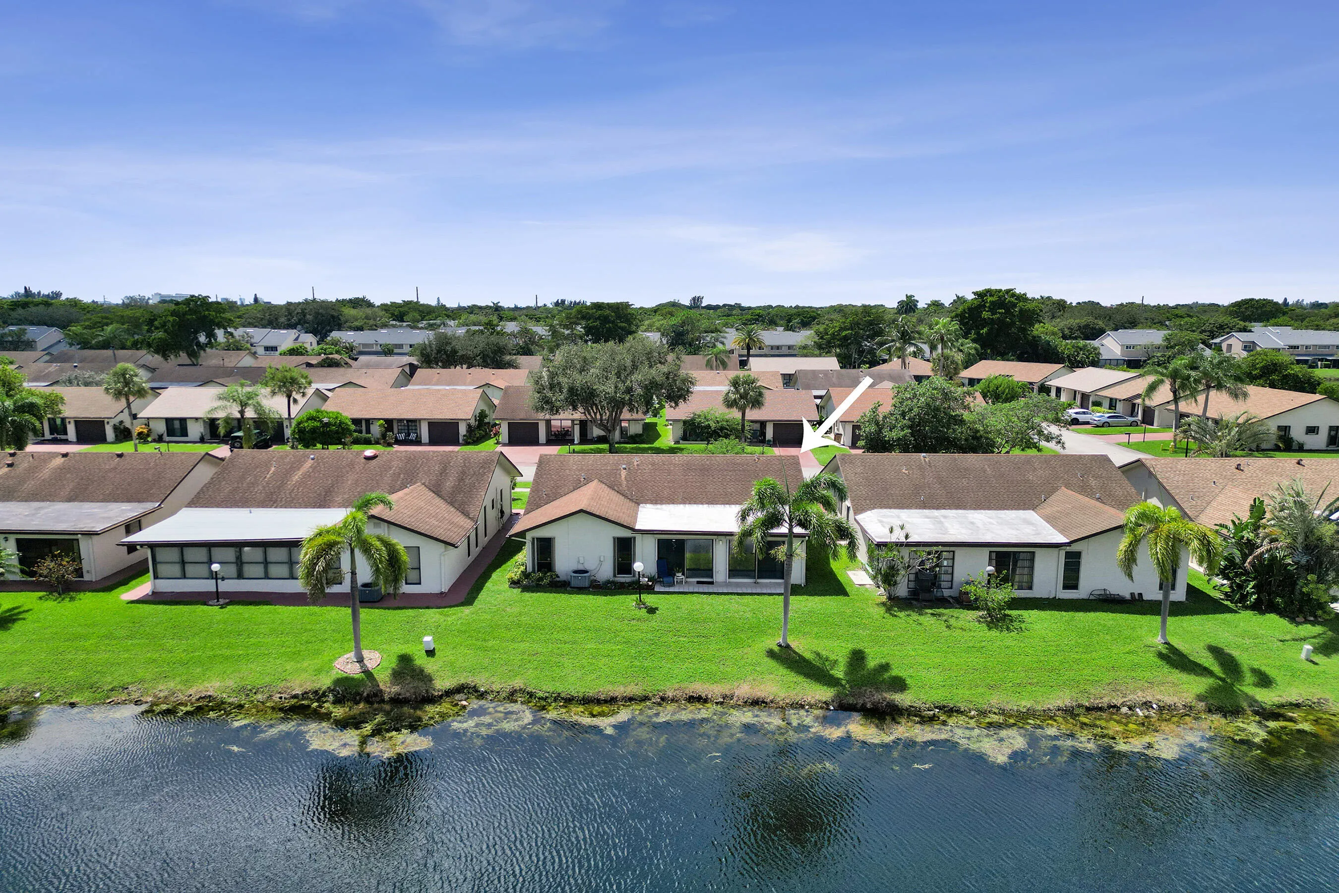 Waterfront property featuring a well-maintained lawn and mature palm trees