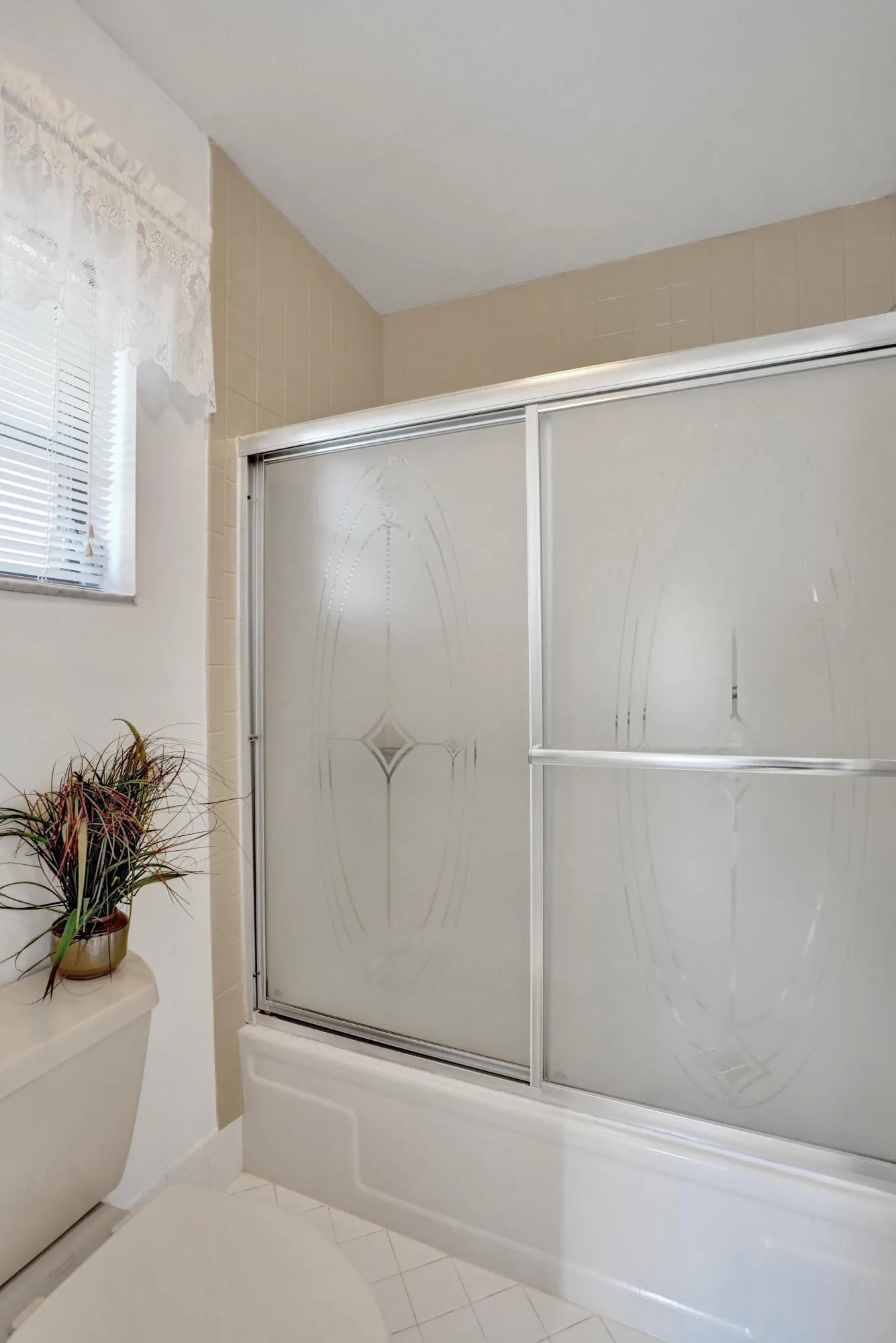 Bathtub with frosted glass sliding shower doors and decorative etching