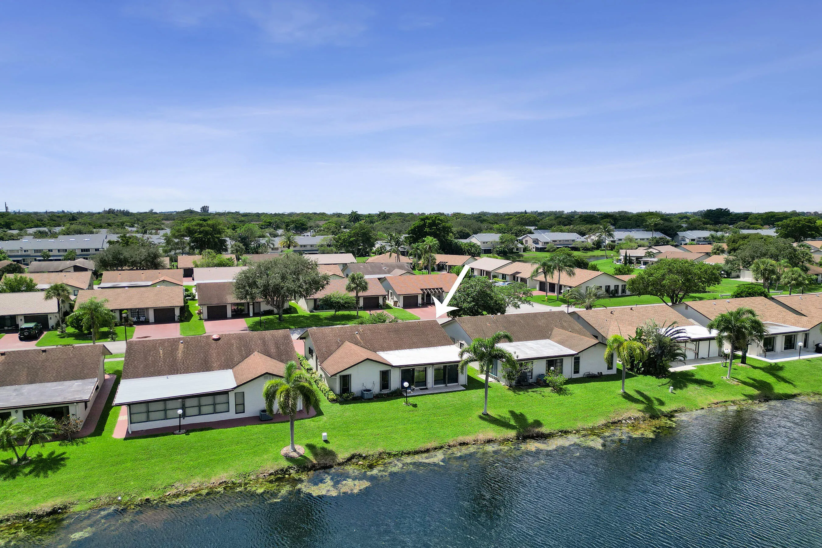 Waterfront property featuring a manicured lawn, mature palm trees, and a covered​​‌​​​​‌​​‌‌​‌‌​​​‌‌​‌​‌​‌​​​‌​​ patio