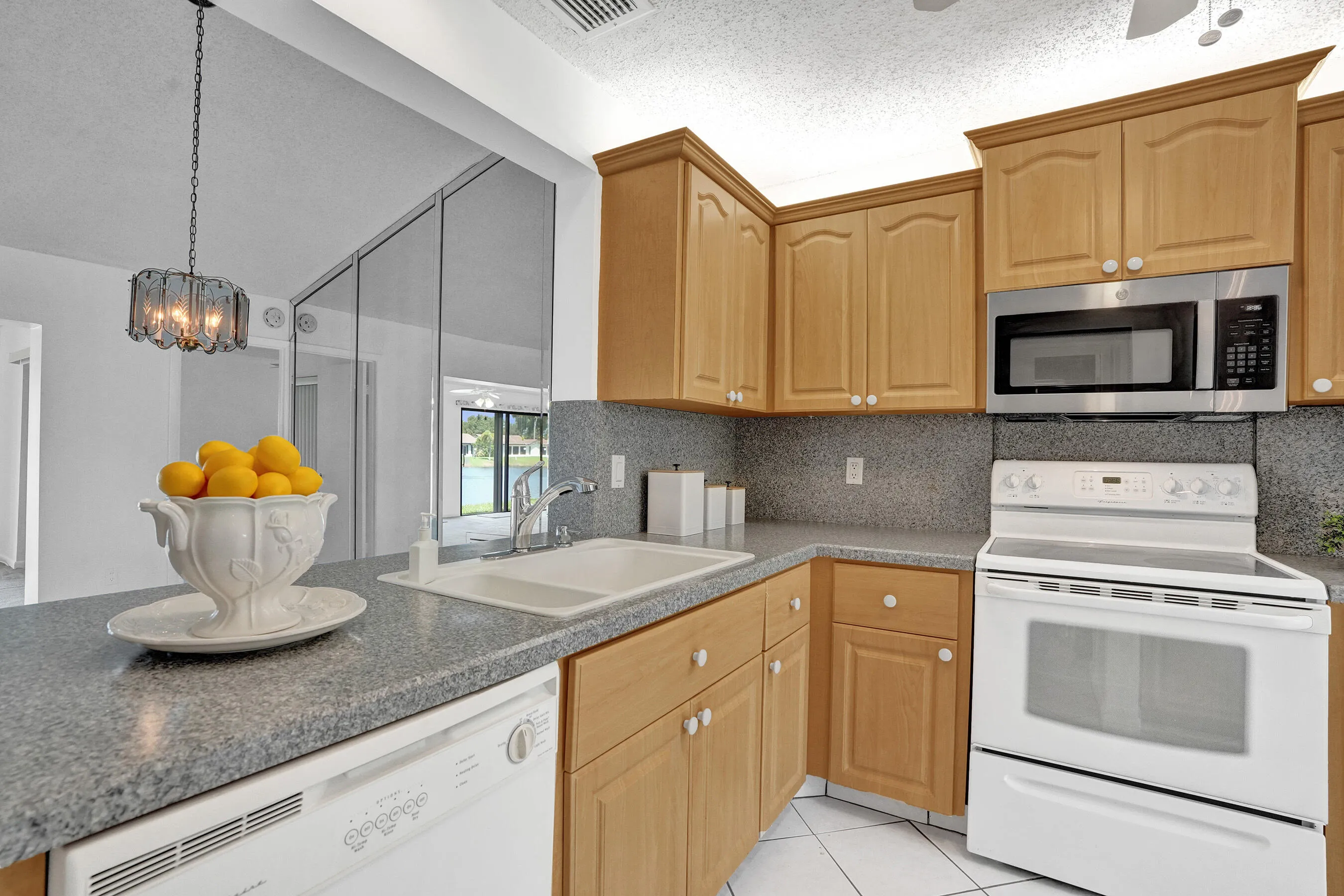 Kitchen featuring wood-finish cabinetry, a stainless steel microwave, a white electric range, and a dishwasher