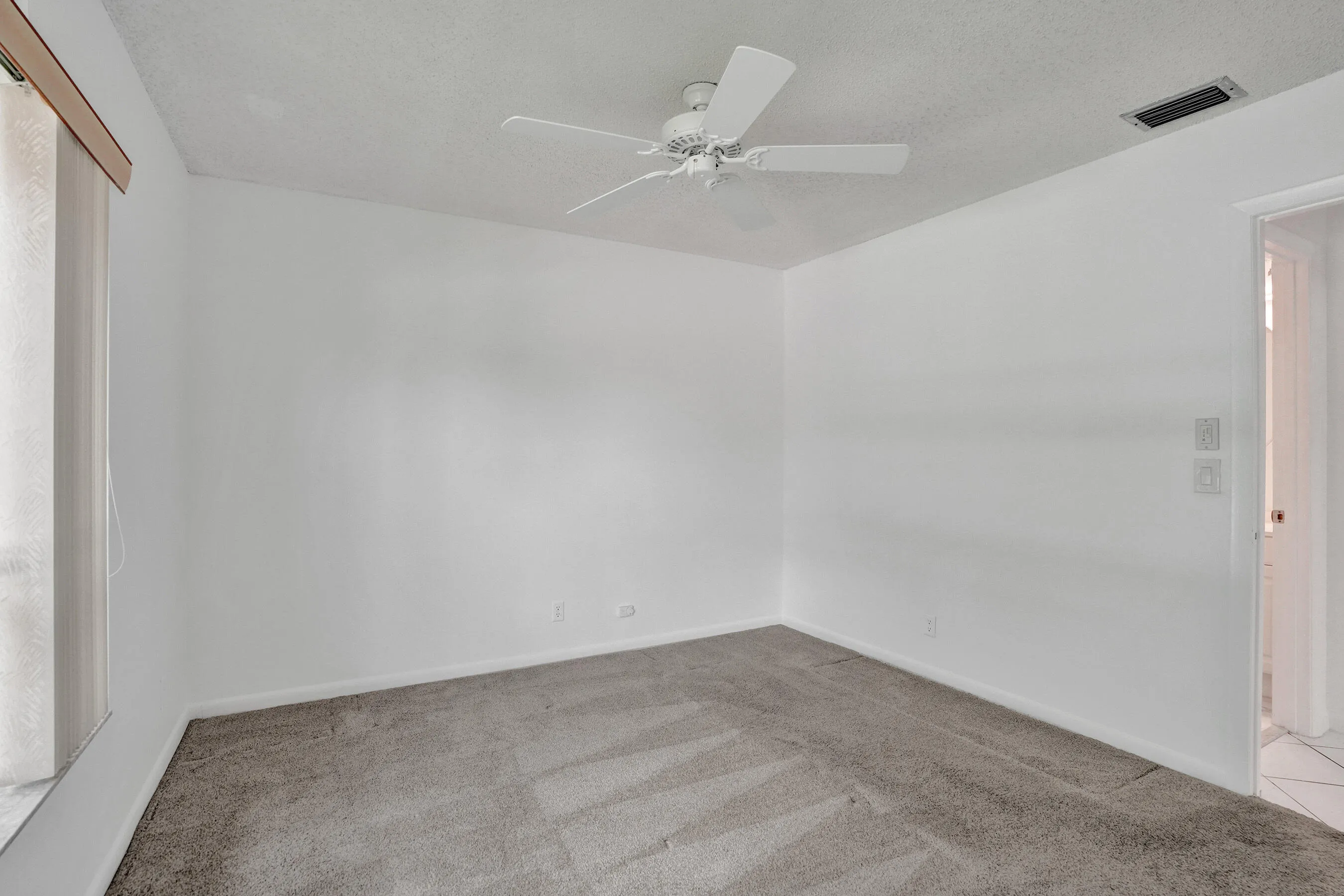 Ceiling fan with light kit, textured ceiling, wall-to-wall carpeting, window with blinds