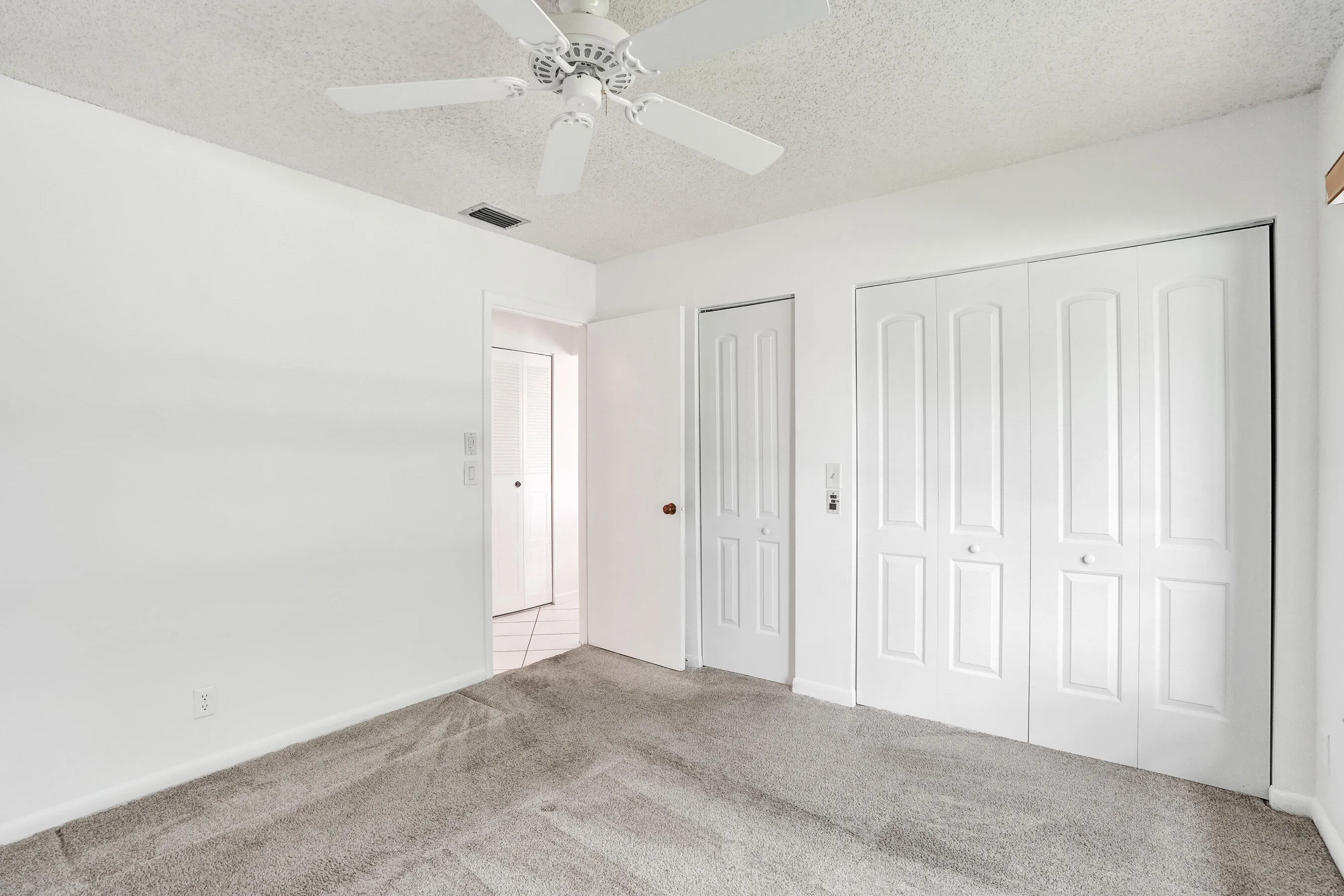 Carpeted flooring, white walls, ceiling fan, bi-fold closet doors