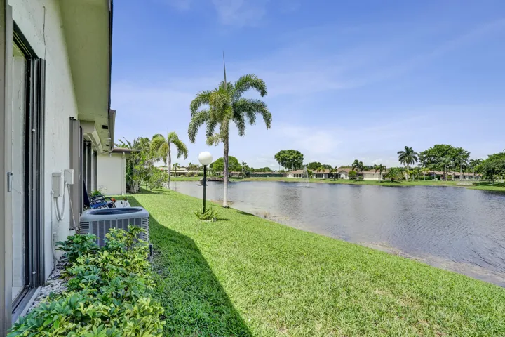 Expansive waterfront lawn featuring mature palm trees and a consistent water body