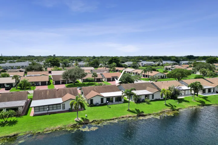 Waterfront property featuring a manicured lawn, mature palm trees, and a covered​​‌​​​​‌​​‌‌​‌‌​​​‌‌​‌​‌​‌​​​‌​​ patio