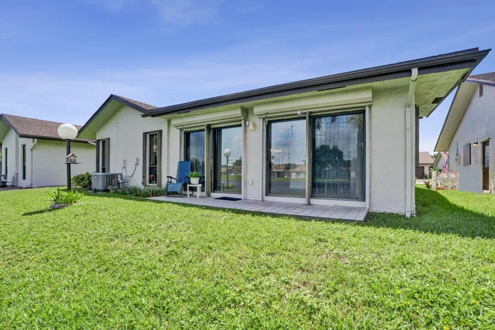 Exterior featuring a tiled patio, multiple sliding glass doors, and a well-maintained lawn