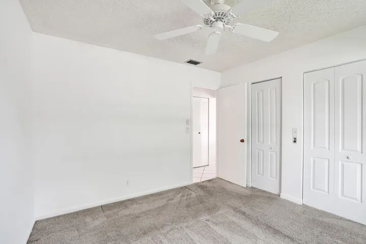 Ceiling fan with light fixture, textured ceiling, light gray carpeting, bi-fold closet doors, white walls