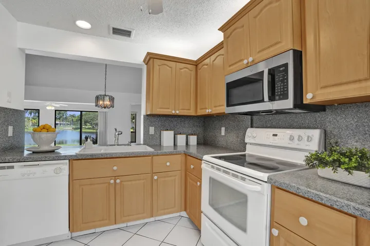 Kitchen featuring wood-finish cabinetry, gray speckled countertops, white appliances, and a stainless steel microwave