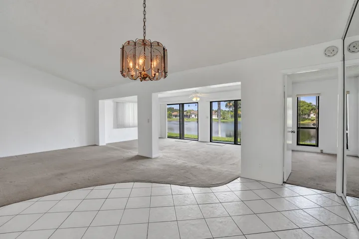 Tile flooring, carpeted areas, suspended chandelier, sliding glass doors, built-in mirrored closet doors