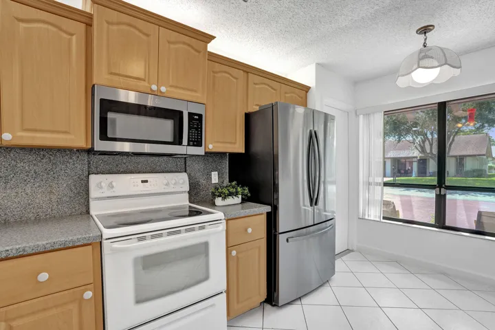Wood-finish cabinetry complemented by light-toned countertops and a matching backsplash