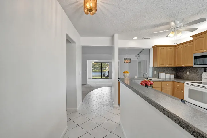 Kitchen with wood-finish cabinetry, built-in microwave, and a breakfast bar with a stone-finish countertop