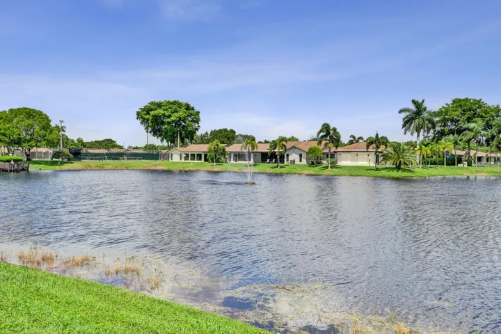 Waterfront property featuring a fountain and lush landscaping with mature palm trees