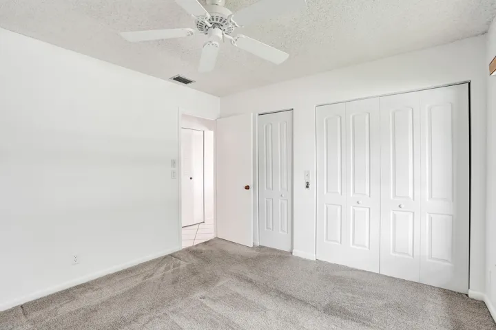 Carpeted flooring, white walls, ceiling fan, bi-fold closet doors