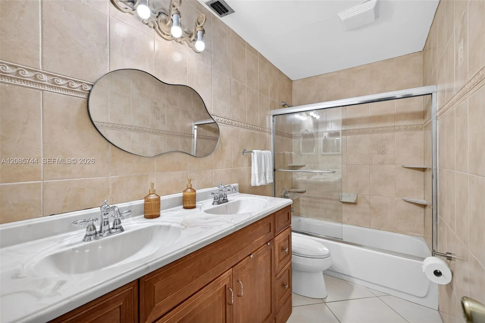 Guest bathroom w/ tub shower combo and dual vanity. Tile to the ceiling and glass enclosure Guest bathroom w/ tub shower combo and dual vanity. Tile to the ceiling and glass enclosure