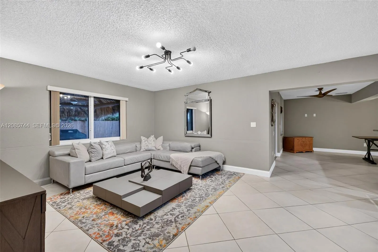 Bright family room / open concept great room – tile on diagonal, pool area behind windows, and leads to french doors to the right, to access pool area Bright family room / open concept great room - tile on diagonal, pool area behind windows, and leads to french doors to the right, to access pool area